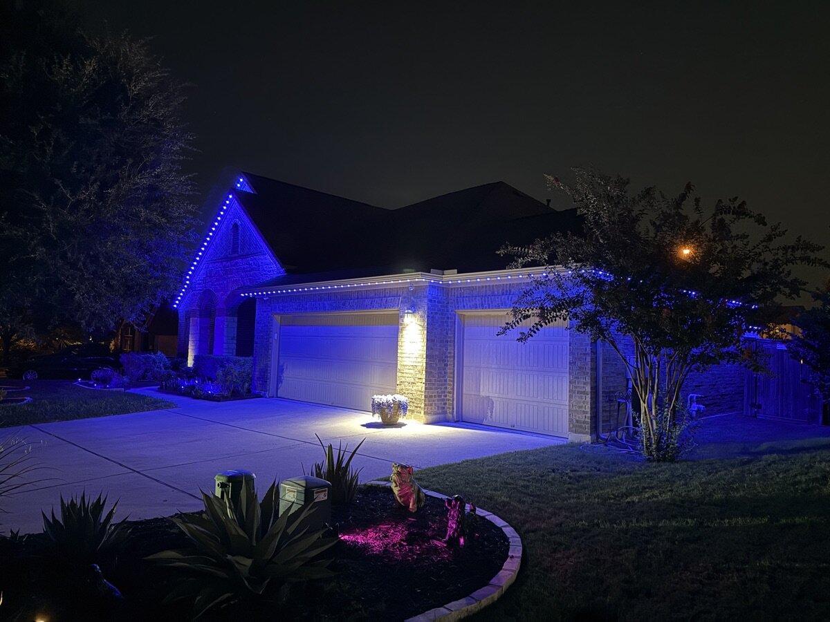 TruLight permanent lighting set to blue on a single-story brick home at night (TruLight Austin install)